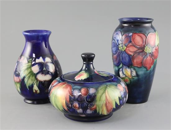 Two Moorcroft vases in clematis and pansy and a similar leaf and berry jar and cover, 1920/30s, H.12.5cm - 18cm